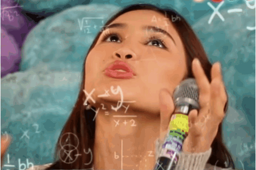A Woman Holds A Microphone In Front Of A Chalkboard With Math Equations GIF