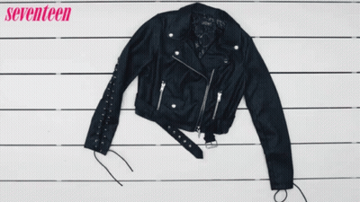 A Woman Holds A Pair Of Black Boots Next To A Plaid Shirt And A Leather Jacket GIF