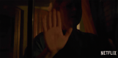 A Woman Holds Her Hand Up In Front Of A Netflix Advertisement GIF