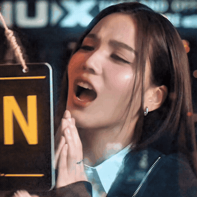 A Woman Holds Her Hands Together In Front Of A Sign That Says N On It GIF