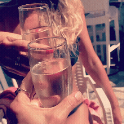 A Woman Holds Up Two Glasses Of Champagne GIF