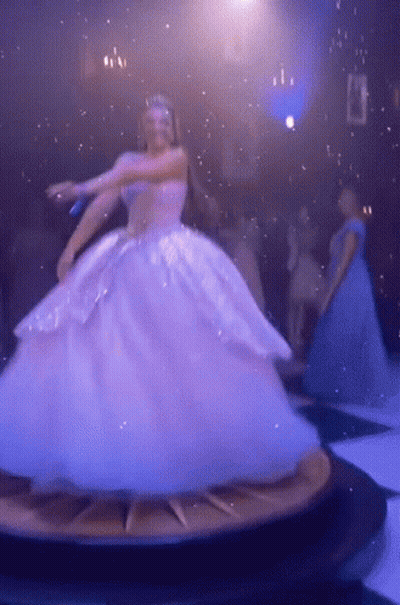 A Woman In A Ball Gown Is Dancing On A Clock GIF