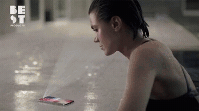 A Woman In A Bathing Suit Is Looking At A Phone That Says Best Products On The Bottom GIF