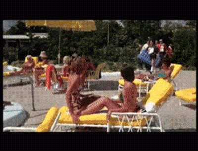 A Woman In A Bathing Suit Sits On A Yellow Chair GIF