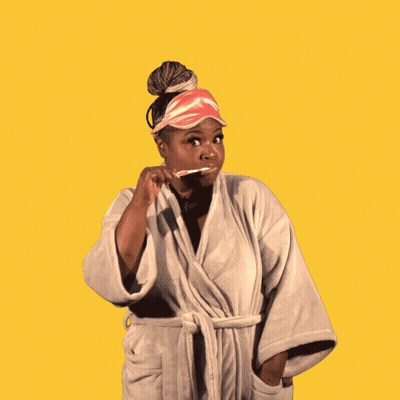 A Woman In A Bathrobe Is Holding A Toothbrush With The Word Good Above Her Head GIF
