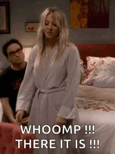 A Woman In A Bathrobe Is Standing In Front Of A Bed And Says Whoomp There It Is GIF