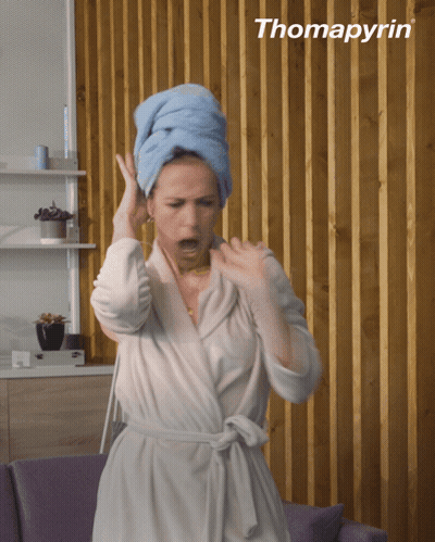 A Woman In A Bathrobe With A Towel Wrapped Around Her Head And The Word Thomapyrin Behind Her GIF