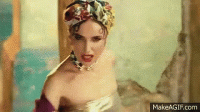 A Woman In A Bathtub Wearing A Turban And A Necklace Is Making A Funny Face . GIF