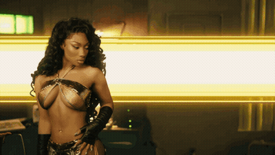 A Woman In A Bikini And Gloves Stands In Front Of A Yellow Light GIF