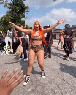 A Woman In A Bikini Is Dancing In Front Of A Crowd . GIF