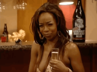 A Woman In A Bikini Is Holding A Glass Of Champagne In Front Of A Bottle Of Bastard Ale . GIF