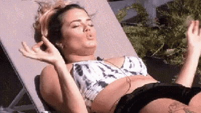 A Woman In A Bikini Is Laying On A Lounge Chair With Her Eyes Closed And Making A Funny Face . GIF