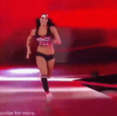 A Woman In A Bikini Is Running On A Stage In A Wrestling Ring . GIF