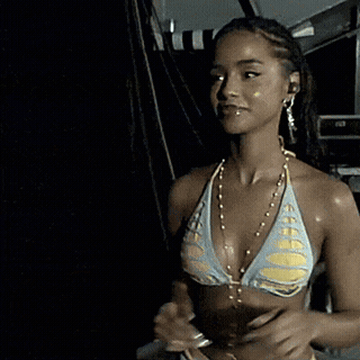 A Woman In A Bikini Is Smiling And Wearing A Necklace GIF