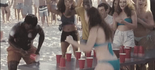 A Woman In A Bikini Is Standing In Front Of A Table With Red Cups On It . GIF