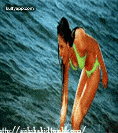 A Woman In A Bikini Is Standing In The Water And The Website Is Kulfyapp.com GIF