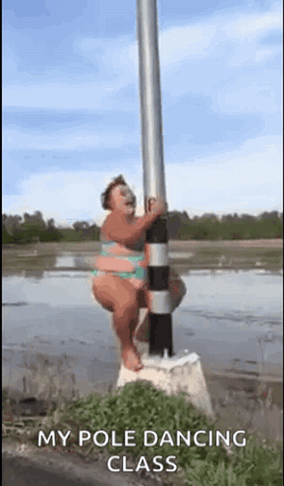 A Woman In A Bikini Is Standing On A Pole In The Water . GIF