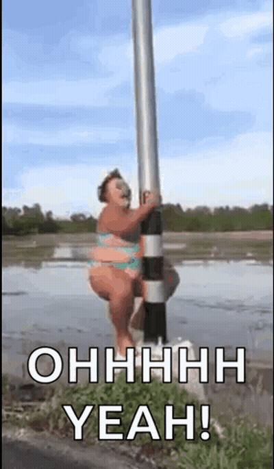 A Woman In A Bikini Is Standing On A Pole In The Water . GIF