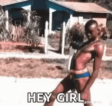 A Woman In A Bikini Is Walking Down The Street And Saying Hey Girl . GIF
