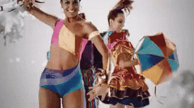 A Woman In A Bikini Stands Next To Another Woman In A Colorful Dress GIF