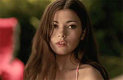 A Woman In A Bikini Top Is Looking At The Camera With A Serious Look On Her Face . GIF