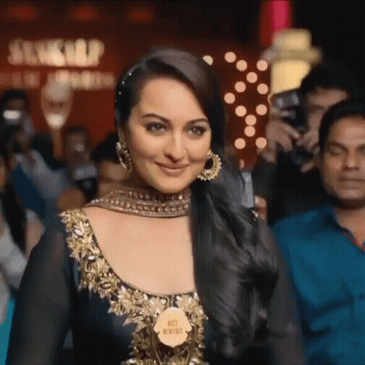A Woman In A Black And Gold Dress Holds A Trophy That Says " Best Newbie " GIF