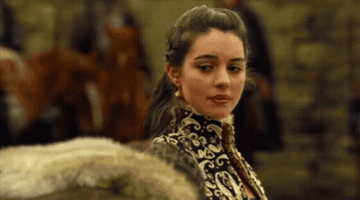 A Woman In A Black And Gold Dress Is Standing In Front Of A Group Of People . GIF
