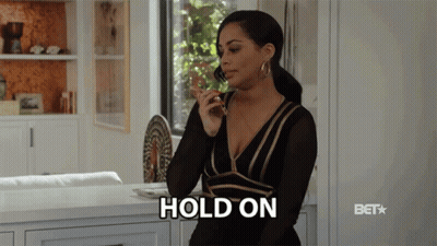 A Woman In A Black And Gold Dress Is Talking On A Cell Phone And The Word Hold On Is Visible GIF
