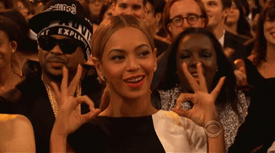 A Woman In A Black And White Dress Is Making An Ok Sign With Her Hands GIF