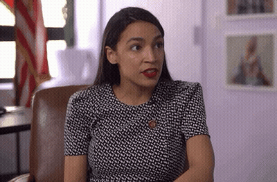 A Woman In A Black And White Dress Is Sitting In A Chair And Looking At The Camera . GIF
