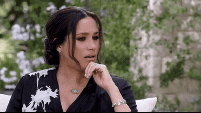 A Woman In A Black And White Dress Is Sitting On A Couch . GIF