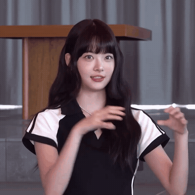 A Woman In A Black And White Dress Is Standing In Front Of A Wooden Podium GIF