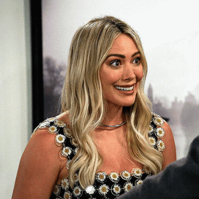 A Woman In A Black And White Floral Dress Smiles GIF