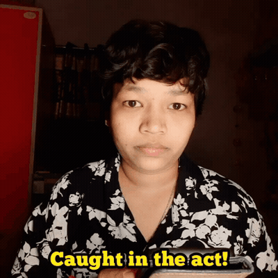 A Woman In A Black And White Floral Shirt Is Holding A Cell Phone And Says Caught In The Act GIF