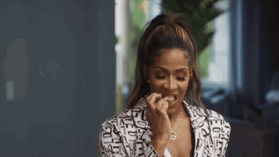 A Woman In A Black And White Jacket Is Eating A Piece Of Food . GIF