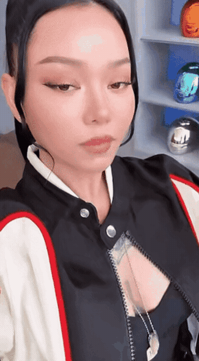 A Woman In A Black And White Jacket Is Taking A Picture Of Herself . GIF