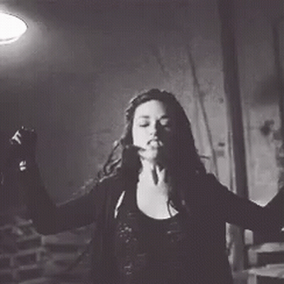 A Woman In A Black And White Photo Is Dancing In A Dark Room . GIF