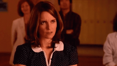 A Woman In A Black And White Polka Dot Dress Is Standing In A Room With Other People . GIF