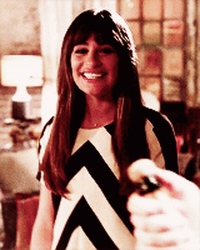 A Woman In A Black And White Striped Dress Smiles While Holding A Bottle GIF