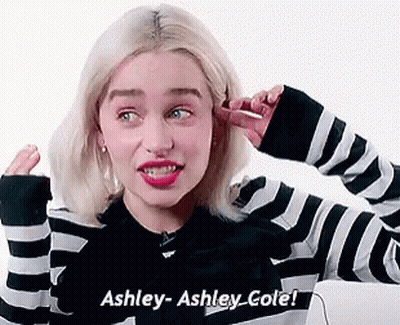 A Woman In A Black And White Striped Sweater Is Covering Her Ears With Her Hand . GIF