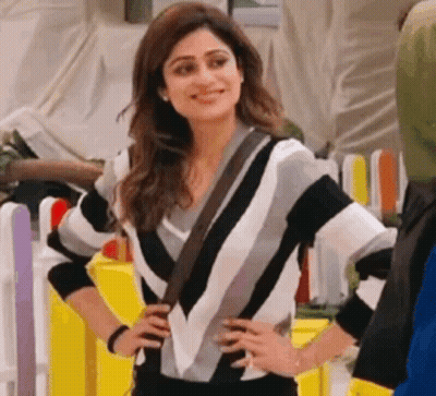 A Woman In A Black And White Striped Sweater Is Standing With Her Hands On Her Hips . GIF