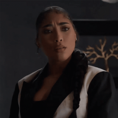 A Woman In A Black And White Suit Is Making An Okay Gesture GIF
