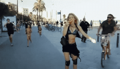 A Woman In A Black Bikini Is Walking Down A Sidewalk GIF