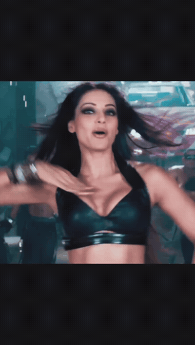 A Woman In A Black Bra Is Dancing In Front Of A White And Red Car GIF