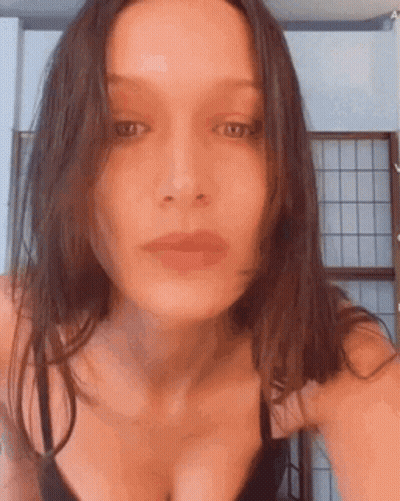 A Woman In A Black Bra Is Taking A Selfie In Front Of A Window . GIF