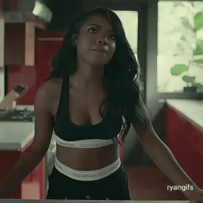 A Woman In A Black Calvin Klein Bra And Black Shorts Is Standing In A Kitchen . GIF
