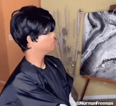 A Woman In A Black Cape Is Standing Next To A Painting . GIF
