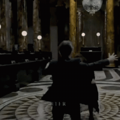 A Woman In A Black Coat Is Dancing In A Room With The Name Bonham Carter Written On The Floor GIF