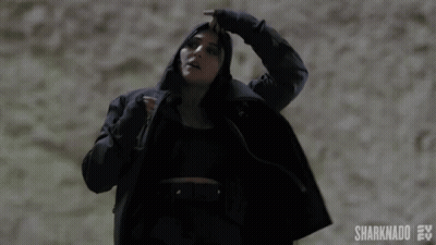 A Woman In A Black Coat Is Holding Her Hair In A Ponytail .. GIF