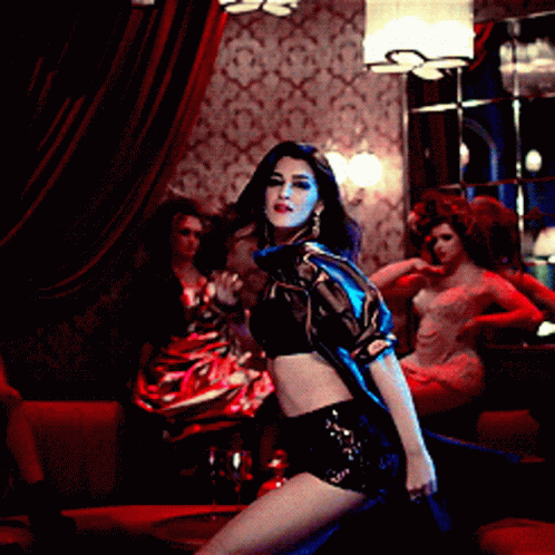 A Woman In A Black Crop Top And Shorts Is Dancing In A Room GIF